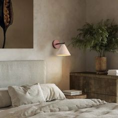 a bedroom with a bed, nightstand and potted plant