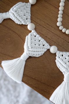 white beads and tassels are arranged on a wooden table with a beaded necklace