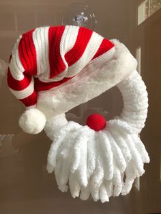 a red and white knitted christmas wreath hanging from a hook