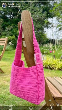 a pink crocheted bag hanging from a wooden chair in front of some grass