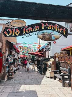 the entrance to an outdoor market with people walking under it