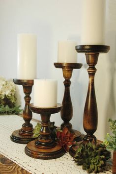 three candles sitting on top of a table next to succulents