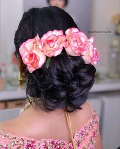 the back of a woman's head with flowers in her hair, wearing a pink dress