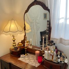 a vanity with a mirror, candles and other items on the table next to it