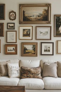 a living room filled with lots of framed pictures on the wall above a white couch