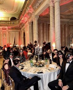 a group of people sitting around a table with masks on