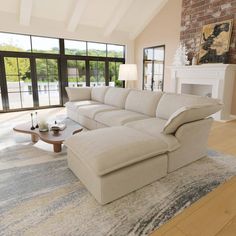 a living room with a large sectional couch in front of a fire place and windows