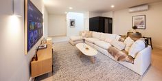 a living room filled with furniture and a flat screen tv mounted to the side of a wall