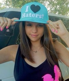 a girl wearing a hat with the word haters on it and holding her hair in front of her face