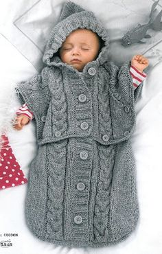 a baby is laying on a bed wearing a coat