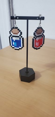 a pair of pixelated earrings on top of a wooden table next to a wall