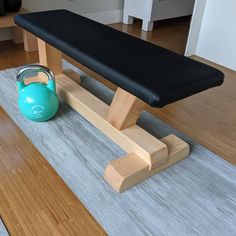 a blue kettle sitting on top of a gym mat next to a black bench with a wooden leg rest