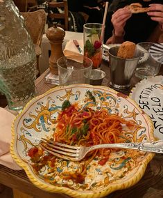 a plate full of spaghetti and sauce on a table with people sitting at the table