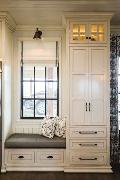 a window seat in the corner of a room next to a refrigerator and cupboards