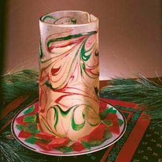 a glass candle holder sitting on top of a plate next to a christmas tree ornament