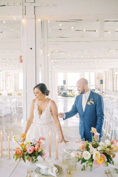 a bride and groom standing next to each other in front of tables with white linens