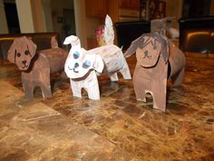 three dogs made out of toilet paper on a table