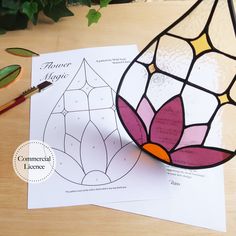 a stained glass vase sitting on top of a table next to paper and pencils