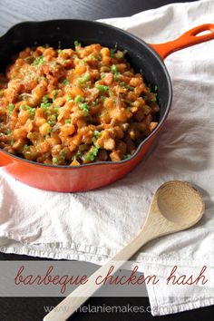 a pan filled with food sitting on top of a white cloth next to a wooden spoon