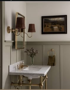 a bathroom sink sitting under a mirror next to a wall mounted faucet with two lamps on it