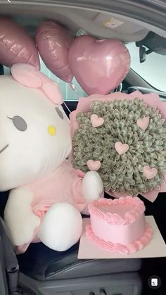 a hello kitty stuffed animal sitting in the back seat of a car next to balloons