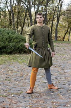 Historically accurate men's woolen cotehardie for reenactors in the medieval style. Ready to ship, a finished item.  Cotehardie features:    - size - L    - 50/50 (industrial / manual) type of sewing    - 100% khaki wool - fabric top    - 100% linen - lining fabric    Item care:      1. Do not hand wash.      2. Dry clean only.      3. A slight dirtying can be easily removed with wet washcloth or clothes brush.      4. Keep on a hanger of appropriate size to avoid deformation. Viking Style Long Sleeve Outerwear For Larp, Medieval Outerwear For Larp With Historical Design, Traditional Long Sleeve Outerwear For Larp, Historical Design Outerwear For Medieval Festivals, Medieval Style Outerwear For Larp And Festivals, Medieval Style Outerwear For Larp And Medieval Festivals, Winter Medieval Dress For Larp With Historical Design, Winter Medieval Dress With Historical Design, Long Sleeve Medieval Dress For Larp