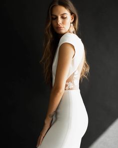 a beautiful woman in a white dress posing for the camera with her hands on her hips