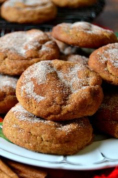 some cookies are on a plate with powdered sugar and cinnamon sticks in the background