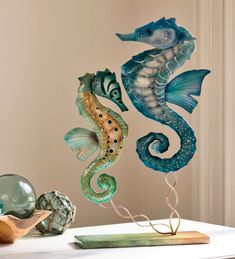 three seahorses sitting on top of a table next to shells and seashells