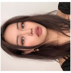 a woman with long brown hair wearing a black shirt and gold necklace, posing for the camera