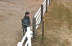 a man standing next to a white fence in front of a horse pen with another person looking over the fence