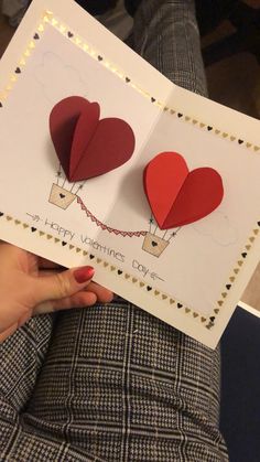 someone holding up two valentine's day cards with paper hearts attached to the card