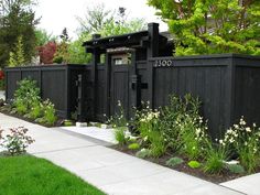 a black fence is surrounded by plants and flowers