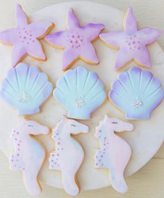 decorated cookies are arranged on a plate with sea shells and starfishs in the shape of seashells