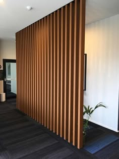 an office with wood slats on the wall and black flooring in front of it