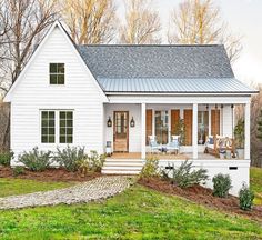 a small white house sitting on top of a lush green field