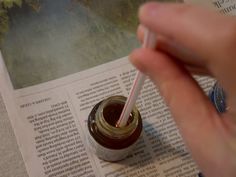 a person is holding a straw in their hand and writing on a book with a pen