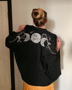 a woman wearing a black jacket with the moon and stars on it's back