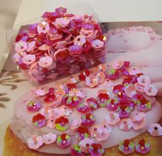 a box filled with pink donuts covered in frosting and sprinkles