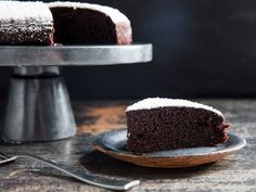 a slice of chocolate cake with powdered sugar on top and a fork next to it