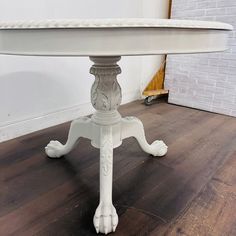 a white table sitting on top of a hard wood floor next to a brick wall