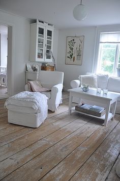 a living room with white furniture and wooden floors