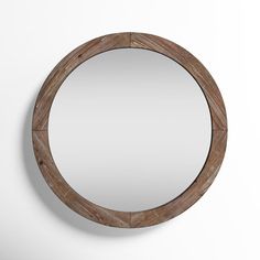 a round mirror hanging on the wall with a wooden frame and metal ring around it