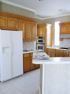 an empty kitchen with wooden cabinets and white counter tops, including a refrigerator freezer