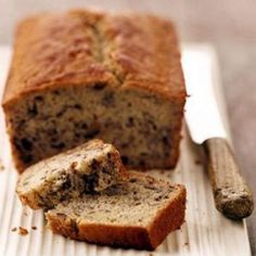 a loaf of banana bread sitting on top of a cutting board next to a knife