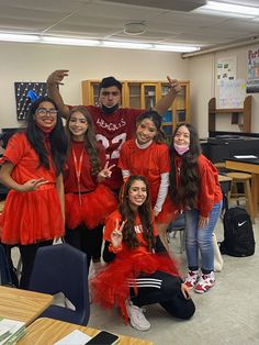 a group of young people dressed in red posing for a photo with their hands up