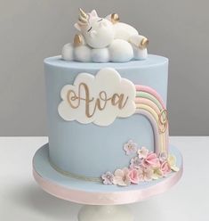 there is a blue cake decorated with unicorns and flowers on it's top