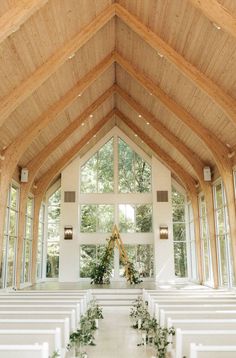 the inside of a church with white pews and greenery