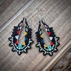 Tiny black, silver, red, blue, yellow and silver seed beads are woven around silver plated hand formed wire loops in a bold geometric pattern. The beaded earrings dangle from graceful sterling silver ear wires and are lightweight. Dimensions: 2.5 inches from the top of the ear wires to the bottom of the beadwork and 1.25 inches at the widest point. You can find more handmade earrings at https://www.etsy.com/shop/windyriver?section_id=5553062 Thank you! Black Southwestern Dangle Earrings, Artisan Black Bead Dangle Jewelry, Artisan Black Beads Dangle Jewelry, Artisan Black Beaded Dangle Jewelry, Southwestern Style Multicolor Jewelry With Black Beads, Multicolor Dangle Jewelry With Black Beads, Handmade Multicolor Teardrop Hoop Earrings, Black Beaded Teardrop Earrings, Black Hoop Earrings With Colorful Beads As Gift