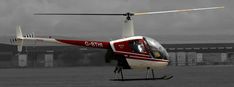 a red and white helicopter sitting on top of an airport tarmac with dark clouds in the background